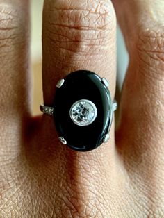 An exceptionally scintillating diamond and onyx cocktail ring. 18K white gold cocktail ring featuring an oval onyx cabochon, approx. 0.40 carats of old European cut diamond and rose cut diamonds at shank. Hallmark: No Hallmark, Tested for 18K Purity Metal Type: 18K White Gold Total Item Weight (g): 5.0 Clarity Grade: SI1 Gemstone: Diamond Fluorescence: Faint Stone Shape: Old European Cut Color Grade: H-I Carat Weight: 0.4 Stone Dimensions (mm): Avg. Diameter 1.05 Clarity Grade: Slightly Included Classic Diamond Ring With Cabochon Cut, Classic Diamond Cabochon Ring, Timeless Diamond Rings With Cabochon, Formal Oval Cabochon Diamond Ring, Oval Cabochon Diamond Ring In White Gold, Oval White Gold Diamond Ring With Cabochon, Art Deco Diamond Rings With Cabochon, Art Deco Diamond Cabochon Rings, Oval Cabochon Platinum Rings