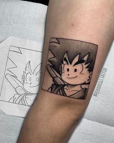 a person with a dragon tattoo on their arm next to a piece of paper that has an image of gohan in it