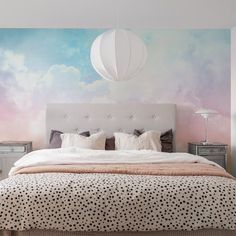 a bedroom with a large bed and sky mural on the wall, along with two nightstands