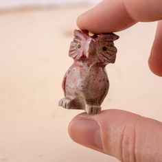 a tiny owl figurine being held by someone's hand