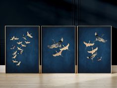 three framed pictures with birds flying in the air on a wooden floor next to a wall