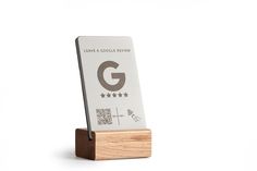 a wooden stand with a business card holder on it's side that has the letter g printed on it