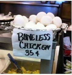 a bunch of eggs sitting in a basket on top of a metal tray with a sign that says boneless chicken 354