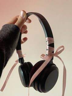 a person holding up headphones with pink ribbons