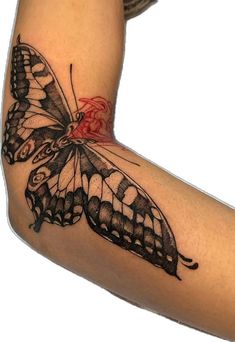 a black and white butterfly tattoo on the right arm, with red flowers around it