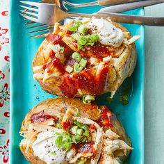 two open faced sandwiches with toppings on a blue platter next to silverware