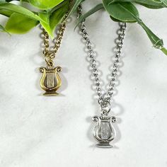 two necklaces that have been placed next to each other on a white surface with green leaves