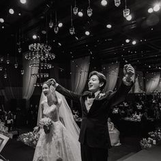 a bride and groom are dancing at their wedding reception in black and white photo with chandeliers hanging from the ceiling