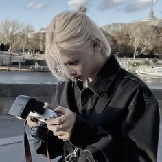 a woman with blond hair is looking at her cell phone