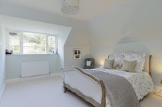 a bedroom with white walls and carpeted flooring has a large bed in the corner