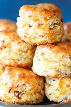 biscuits stacked on top of each other in a metal bowl with cheese and bacon toppings