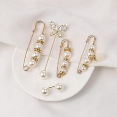 three pairs of pearl and gold earrings on top of a white plate with a butterfly