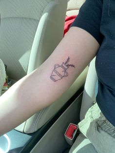 a person with a tattoo on their arm in the back seat of a car,