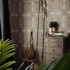 a room with a chest of drawers and wallpaper