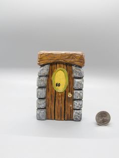 a small wooden door with a hole in the middle and a coin next to it