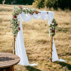 an outdoor wedding setup with white draping and red flowers on the arbors