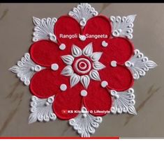 a red and white flower is shown on the floor with text that reads rangoli b sanpeta