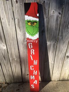 a snowboard with the grin on it is leaning against a wooden fence that says merry