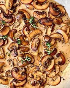 a pizza topped with mushrooms and herbs on top of a pan