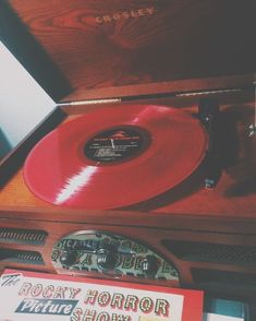 an old record player with red vinyl on it's turntable, and other records