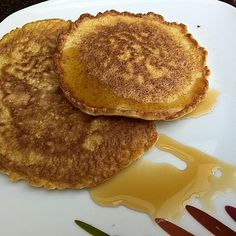 two pancakes sitting on top of a white plate covered in syrup and melted chocolate sauce