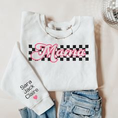 Trendy and cute, Perfect gift for mom for Mothers day, moms birthday, baby showers and more! Checkered Mama Embroidered sweatshirt, Mama Crewneck Sweatshirt, Pregnancy Reveal Gift for New mom, Custom Mom Shirt with Kids Names, Mama Sweater This cute and trendy sweatshirt features our fun checkered print "MAMA" embroidery design, and list of names embroidered on a sleeve with a matching heart. Default design colors are hot pink, and black or white. Other thread colors can be used upon request. *C Customizable Casual Sweatshirt For Mother's Day, White Tops With Embroidered Graphics For Mother's Day, White Embroidered Tops For Mother's Day, Casual Sweatshirt For Birthday And Mother's Day, White Cotton Sweatshirt For Mother's Day, White Casual Sweatshirt For Birthday, Casual White Sweatshirt For Birthday, Family Matching White Sweatshirt With Letter Embroidery, White Family Matching Sweatshirt With Letter Embroidery