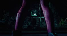 two pink legs in front of a house at night