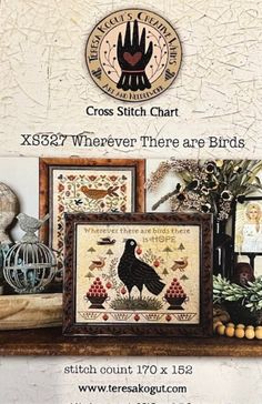 the cross stitch chart is displayed in front of a shelf with pictures and other items