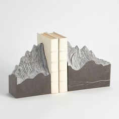 The Pair Mountain Summit Bookends are made of chiseled grey graffito marble. Dimensions Overall 14"L x 3.5"W x 9"H (24.69 lbs) Small bookend 6"L x 3.5"W x 8"H Large bookend 8"L x 3.5"W x 9"H  Clean with dry cotton cloth Mountain Summit, Baby Diy Projects, Octagon Table, Cement Art, Bar Accessories Decor, High Point Market, Gray Marble, Global Views, Outdoor Pendant