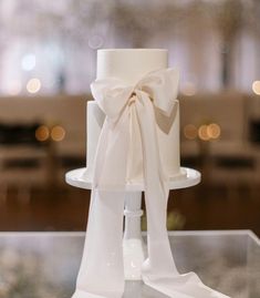 a white wedding cake with a large bow on it's top sitting on a table