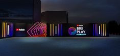 the big play sign is lit up in front of a building with neon lights on it