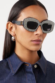 Spotted on the Fall '23 runway, LOEWE Eyewear's sunglasses are made from navy acetate and covered in glistening crystals, capturing attention from every angle. They have oversized, square frames with smoked gray lenses and gold-tone logos at the arms.