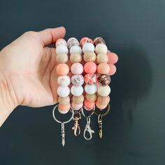 a hand holding a bunch of different colored beads and keychains with charms attached to them