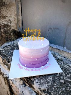 a birthday cake sitting on top of a white card with pink and purple frosting