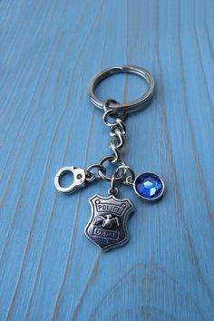 a keychain with a police badge and a blue crystal bead on it