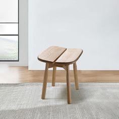 two wooden stools sitting on top of a rug in front of a white wall