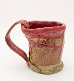 a red and gold mug sitting on top of a white table