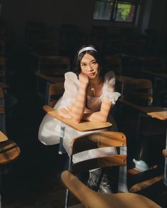 a woman sitting in a classroom chair with her hand on her chin