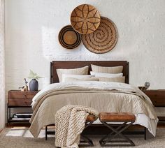 a bed with white sheets and pillows in a bedroom next to two baskets on the wall