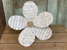 a paper flower with sheet music notes on it sitting on top of a wooden table