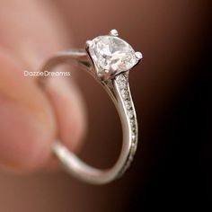 a close up of a person's hand holding a ring with a diamond on it