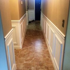 an empty hallway with white trim and brown flooring