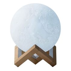 the moon lamp is sitting on top of a wooden stand with a white light inside