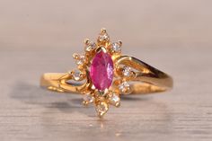 Tres Calle: 1980s Original Ruby and Diamond Ring in Yellow Gold. This captivating ring features a central marquise brilliant cut natural ruby surrounded by a halo of round cut natural diamonds. The ring is elegantly finished with a split sweeping shank, adding a touch of sophistication to the design. Crafted with meticulous attention to detail in 14 karat yellow gold, this ring is currently a finger size 6.5 but can be adjusted to any finger size for an additional charge upon request. Love this Ruby And Diamond Ring, Knot Ring, Natural Ruby, Rose Cut Diamond, Rings Statement, Round Cut, Statement Rings, Natural Diamonds, Halo