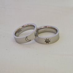 two wedding rings with the sun and moon engraved on each one, sitting on a white surface