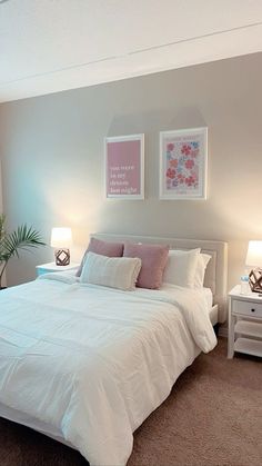 a white bed sitting in a bedroom next to two lamps on either side of the bed