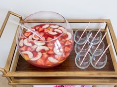 there are glasses and strawberries in the bowl on the tray next to each other