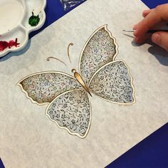 a person is painting a butterfly on paper