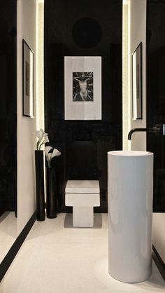 a white toilet sitting next to a sink in a bathroom under two framed pictures on the wall