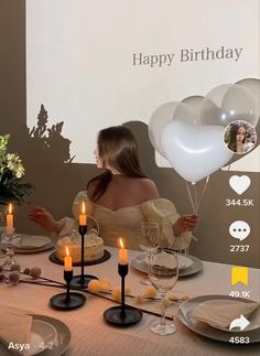 a woman sitting at a table with balloons and candles